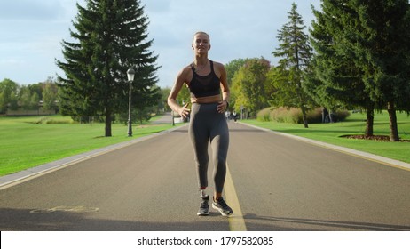 Handicapped Woman Running In Park. Female Runner Training On Asphalt Surface In Slow Motion. Front View Sportswoman Doing Cardio Workout Outdoors. Runner Woman Running Outside