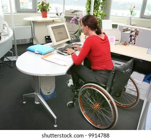 handicapped woman in wheelchair in a office working on a computer