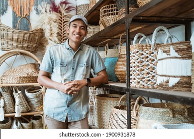 handicraft business owner with his hands leaning back on a shelf while in a handicraft shop with crafts in the shelf background