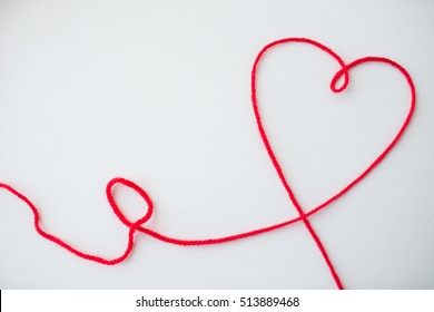 handicraft, love, valentines day, healthcare and needlework concept - red knitting yarn thread in shape of heart