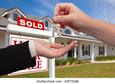 Handing Over The House Keys In Front Of Sold New Home Against A Blue Sky