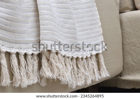 a hand-knitted yarn blanket on a beige couch