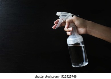 Handle A Spray Bottle To Spray Water Mist In The Air Against A Black Background.