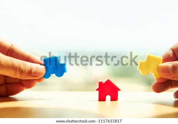 \
Handles hold home model and car and house model on wooden\
boards.Have a background office.Credit or loan and earning for home\
in the family.Use money to exchange or buy in business\
