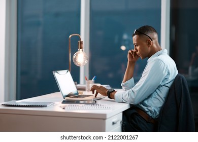 Handling Business His Own Way. Shot Of A Handsome Young Businessman Working On His Laptop During A Late Night Shift At Work.