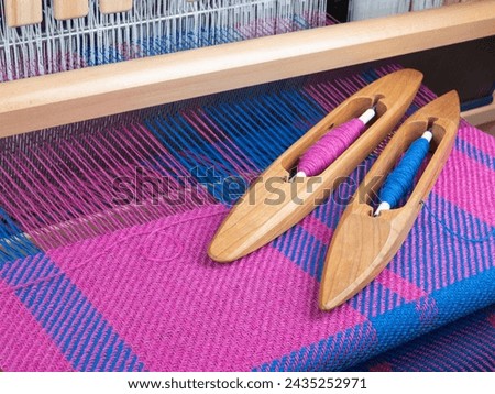 Handloom and shuttles with threads, selective focus. Combination of pink and blue colors. Weaving concept
