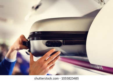 Hand-luggage compartment with suitcases in airplane. Hands take off hand luggage. Passenger put cabin bag cabin on the top shelf. Travel concept with copy space