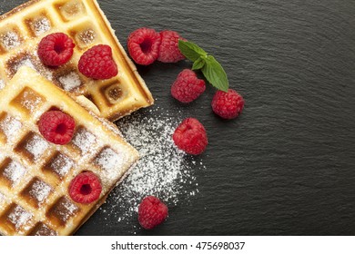 Handmade Belgian Waffles With Raspberries And Icing Sugar On Black Slate, Closeup