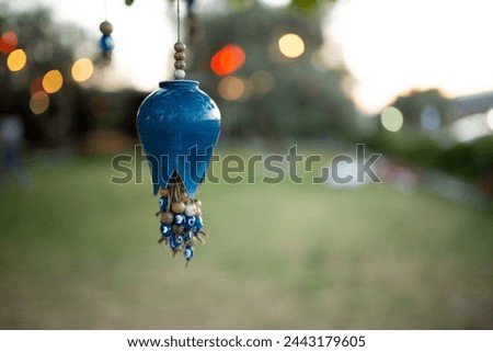 Handmade blue beads hanging from a tree branch in the garden. Colorful tree decorations hanging on a tree in the garden. lantern with beads hanging on the tree in the park at sunset.