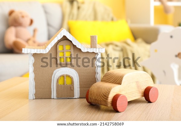 Handmade\
cardboard house and wooden car on\
table
