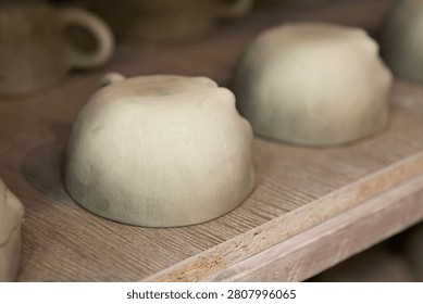 Handmade Ceramic Cups Drying on Shelves Before Kiln Firing in Pottery Workshop