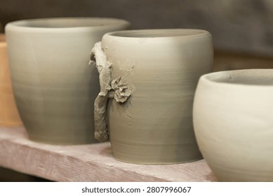 Handmade Ceramic Cups Drying on Shelves Before Kiln Firing in Pottery Workshop