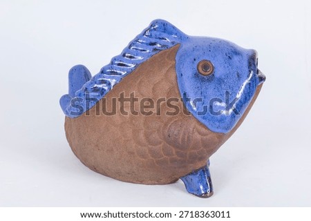 Handmade ceramic fish decorative object in blue and sand colors on a white background. Macro detail shot, different compositions, abstract pastel, interesting and varied background images.