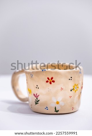 Hand-made ceramic mug with colorful flowers on white background