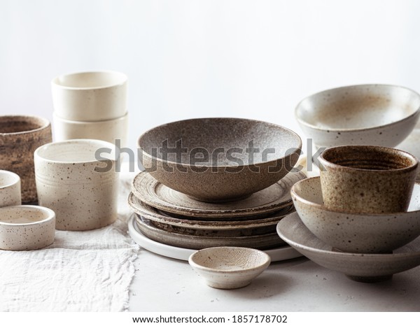 handmade ceramic tableware, empty craft\
ceramic plates, bowls and cups on light background\
