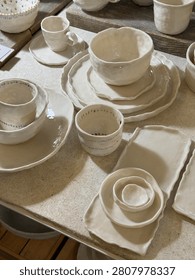 Handmade ceramic tableware set on wooden table showcasing artisanal craftsmanship. Mobile photo
