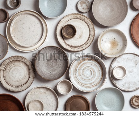 handmade ceramics, empty craft ceramic plates and bowls on light background, top view