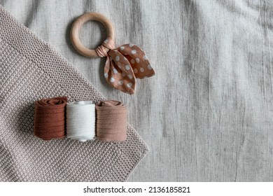 Handmade children's goods in the form of children's socks rolled up in a tube and pacifiers - a teether in the form of a wooden ring with a rag bow in polka dots. Top view.