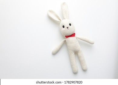 Handmade children's toy - soft crocheted white Bunny. Large knitted stuffed rabbit with eyes made of buttons on white background - the concept of happy childhood