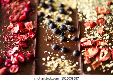 Handmade chocolate bars with dried cranberries, raspberries and pistachios, strawberries, nuts. Dark and milk chocolate mix, assortment. Top view.