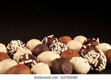 Handmade chocolate bonbon, luxury handmade chocolate bonbon with copy space black or dark background. Assorted pralines with selective focus on black background, close up view.