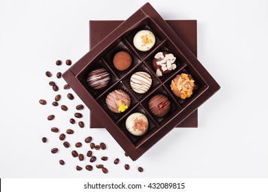 handmade chocolates in a square box and coffee beans near (top view)