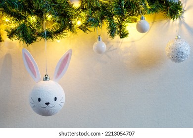 Handmade christmas ball with ears in form of bunny hanging on the christmas tree. Happy Chinese new year of the rabbit zodiac sign. Symbol of the year 2023.