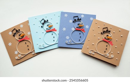 Handmade Christmas cards. Creative paper Christmas snowmen and the snow. Snowman in red scarf in winter. Homemade paper New Year's greeting cards ready to be gifted. Technique of paper quilling - Powered by Shutterstock