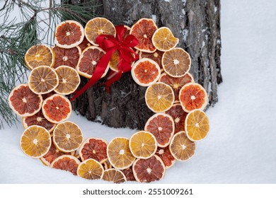 Handmade Christmas wreath from dried orange grapefruit slices. Festive holiday decor in snowy outdoors winter weather. Sustainable responsible holiday gift. Greeting card copy space  - Powered by Shutterstock