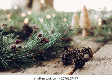 Handmade Christmas wreath with pinecones and red berries on rustic wood table, Countryside advent Christmas celebration with fir garland, candle, and Christmas lights - Powered by Shutterstock