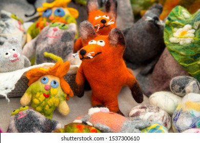 Handmade colorful childhood felted toys in shape of fat funny fox, colorful brownie. Cozy handmade felted woolen dolls on the outside street market on harvest day festival market. Gift for baby 