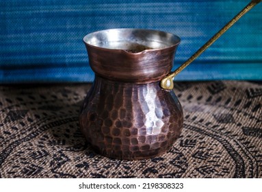 Handmade Copper Coffee Mug With A Brass Handle On The Background Of Decor Made Of Natural Materials. Still Life Photo In Vintage Ethnic Style.