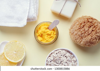 Handmade Cosmetics, Organic Fruit  Mask In Glass Jar, Milk Soap, Slices Of Lemon, Oat Flakes, White Towel And Sea Sponge On Yellow Background, Top View, Flat Layout