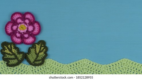 Handmade Crochet Flower On A Blue Textile Background.