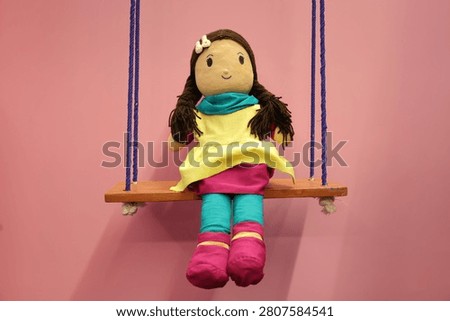 A handmade doll sitting on swing. Kids toy baby doll