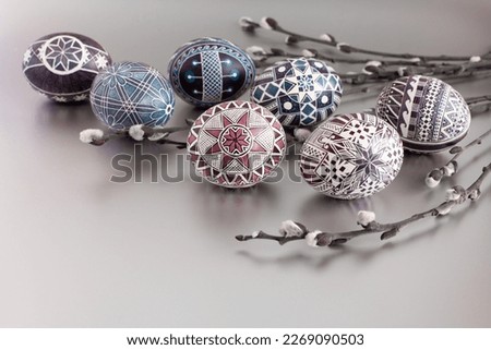 Handmade Easter eggs on a silver background with willow twigs