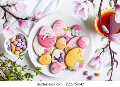 Handmade Easter gingerbread cookies and chocolate eggs in a white plate on a white  background.