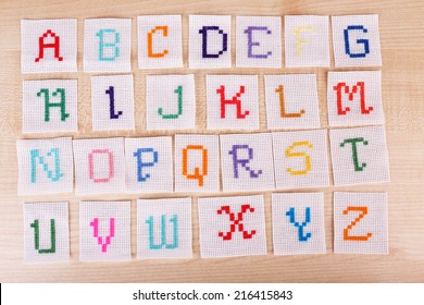 Handmade Embroidered Letters On White Fabric, On Wooden Background