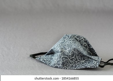 Handmade Fabric Mask On A Silver Background, Celebrate Winter With Holly And Curved Lines On A Gray Mask
