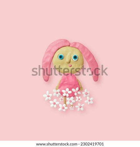 Handmade girl in daisies. Little girl with pink hair and pink dress. Modeling clay.