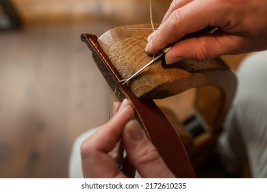 Handmade. the girl sews a leather belt in the workshop. Wooden machine. Atmospheric photo. Close up - Shutterstock ID 2172610235
