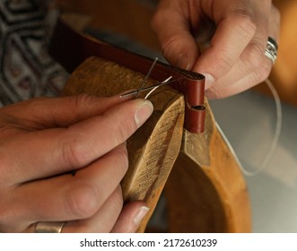 Handmade. the girl sews a leather belt in the workshop. Wooden machine. Atmospheric photo. Close up - Shutterstock ID 2172610239