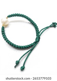 Handmade green macrame bracelet with a single white pearl and gold accents. Adjustable cord design on white background. Elegant boho jewelry style, perfect for casual or formal wear.