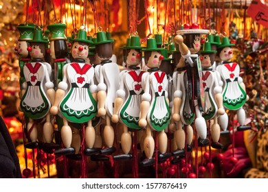 Handmade Hanging Wooden Christmas Ornament Female Figures In Green And White Dress Against A Out Of Focus Red/orange Back Drop