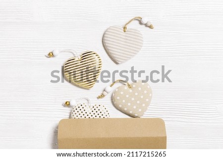 Handmade hearts from cotton cloth with golden color striped or dots and white empty paper for love message on white wood background. Valentines Day greeting card with copy space. Valentine postcard