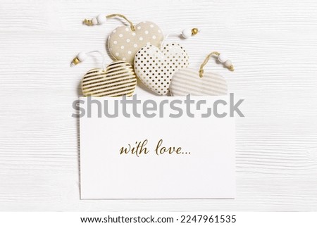 Handmade hearts from cotton cloth with golden color striped or dots flying from envelope, white wood background. Valentines Day concept, holiday greeting card, text with love. Valentine postcard