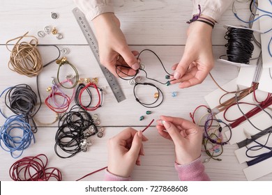 Handmade jewelry making, female hobby. Two women creating bracelets at home workshop, top view on workplace. Fashion, handicraft concept