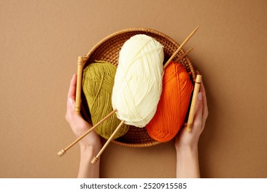 Handmade knitting essentials: colorful yarn balls in green, white, and orange with wooden needles in a wicker basket. Perfect for craft, hobby, and DIY project themes - Powered by Shutterstock