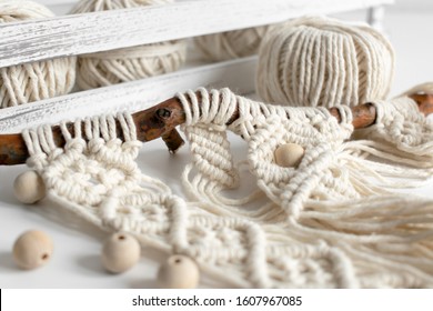 Handmade macrame braiding and cotton threads on rustic wooden stick. Boho image good for macrame and handicrafts banners and advertisement