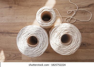 Handmade macrame braiding and cotton threads on rustic wooden table. Hobby knitting cotton thread reel on a wooden board. Female hobby. Top vew